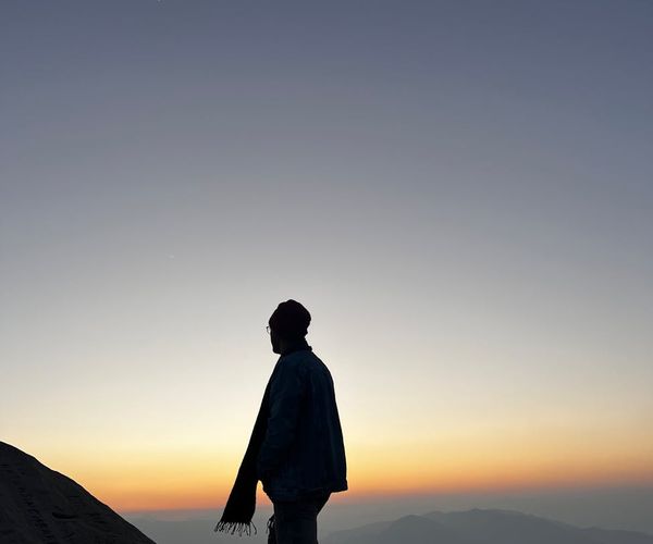 Silhouette of a man stretching against a sunrise.